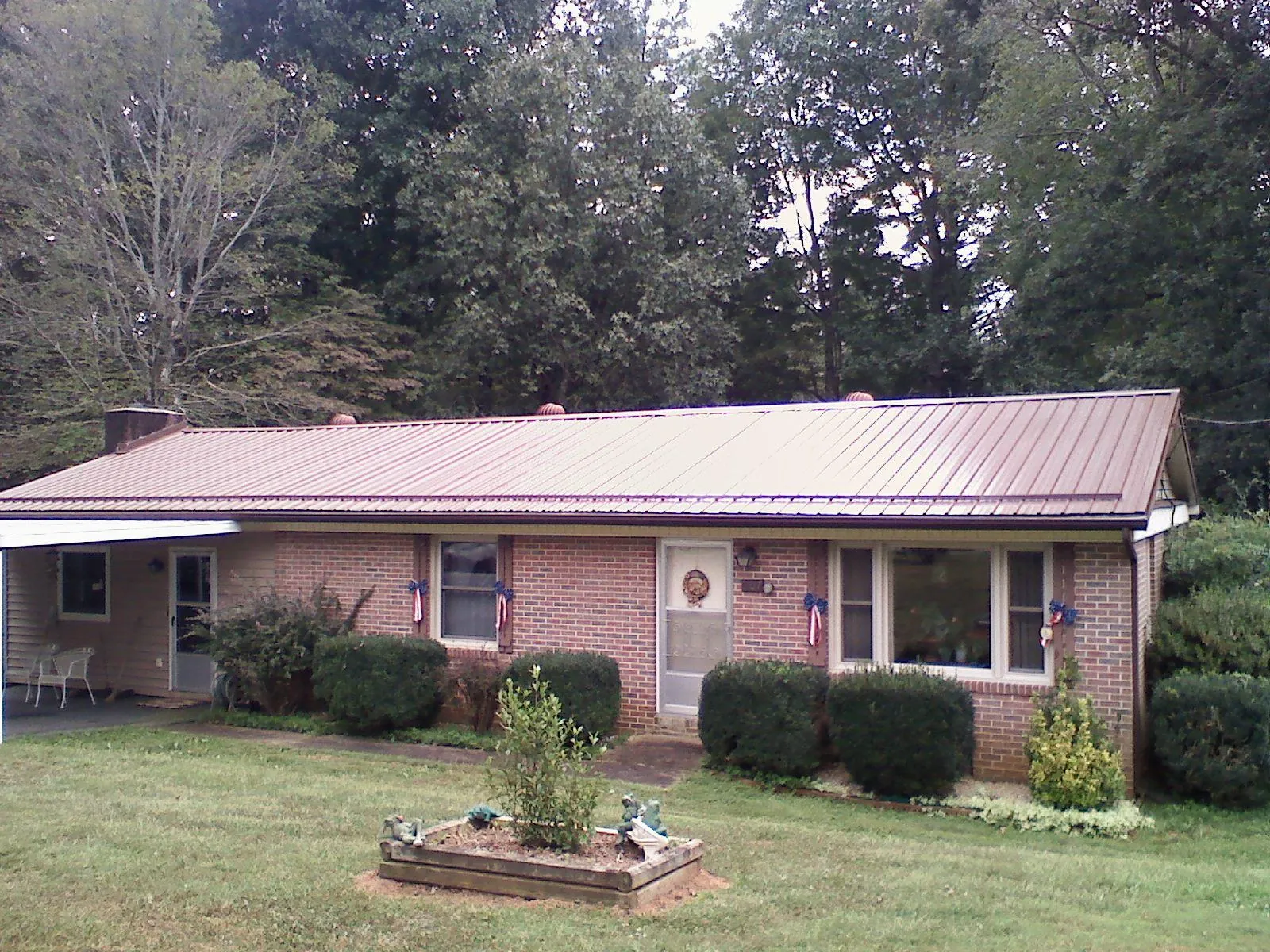 Bronze metal roof on a brick ranch home with a carport in Alamo