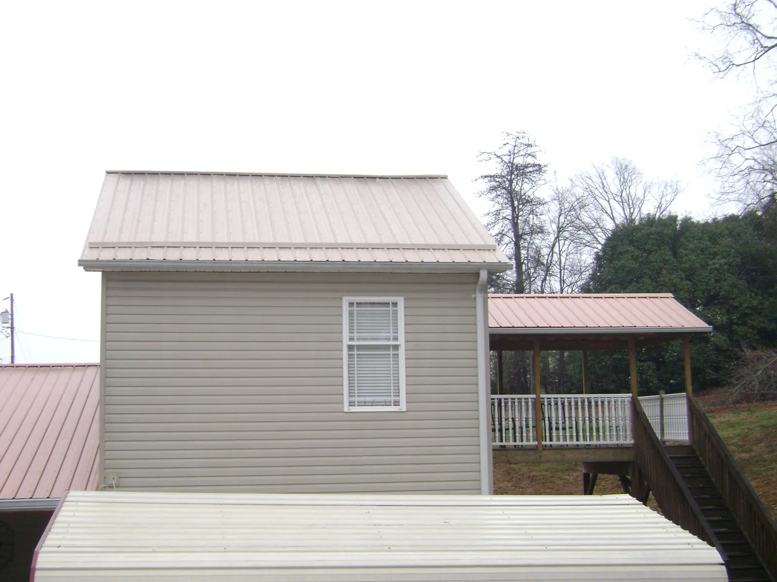 Tan metal roofs on a two story addition and attached porch, from a Roof Replacement job in Alamo